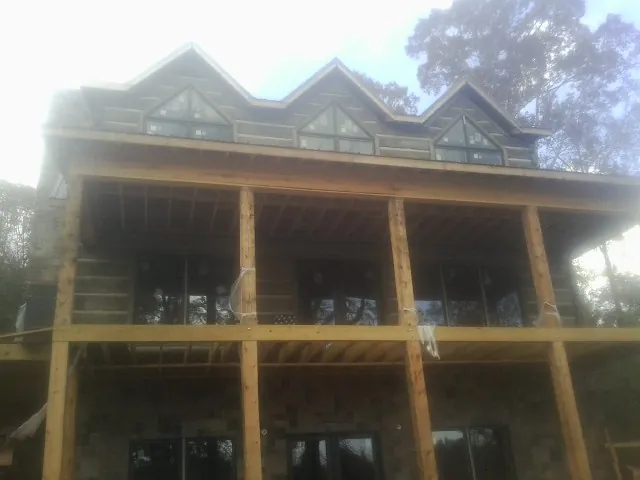 Dormers and porch framing on a large log home under construction — Roof Coating work by our crew in Luna Pier