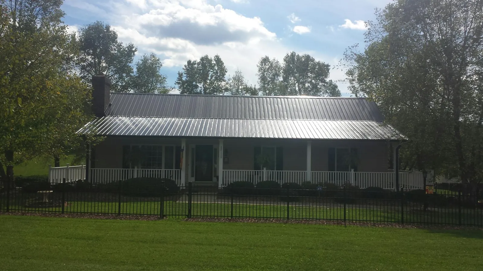 Gray metal roof on a brick ranch with a full width front porch — Gutter Guard Installation work by our crew in Luna Pier