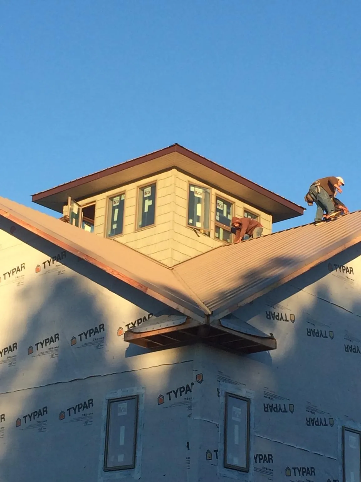 Roofers working around a rooftop cupola on a new metal roof at sunset — Roof Waterproofing in Luna Pier by Roofing Brothers